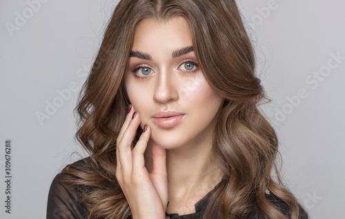 Portrait of a beautiful happy woman with long eyelashes, beautiful fresh nude make-up, thick eyebrows and with clean skin in a beauty salon. Eyelash extensions. Face close-up. Make-up concept