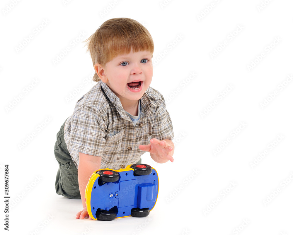 Portrait of a charming smiling little boy playing on the floor with a yellow car on a white background. Concept of preschool children and children games. Advertising space Portrait of a charming smiling little boy playing on the floor with a yellow car on a white background. Concept of preschool children and children games. Advertising space