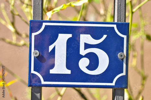 A house number plaque, showing the white coloured number fifteen (15)