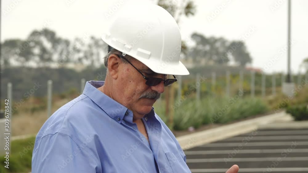 Mature adult landscape architect using a tablet computer to take photos of a job site
