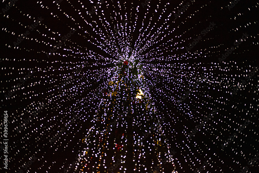 Obraz premium Christmas tree decorated with bright lamps. Big tree delivered for christmas. A lot of LEDs on the tree. Design of park illumination on holidays. Elegant city lighting.