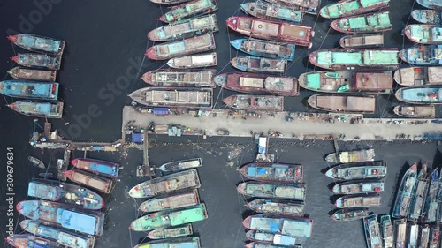 Top down view of wooden fisherman boats anchoring in Muara Angke harbor in Jakarta, Indonesia. Shot in 4k resolution from a drone flying from left to right photo