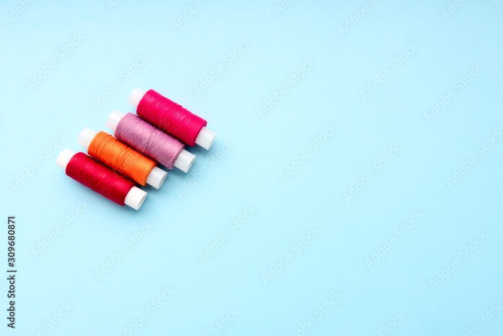 Colored bright threads on a blue background. Close-up. Top view is for place text. Colored bright threads on a blue background. Close-up. Top view is for place text.