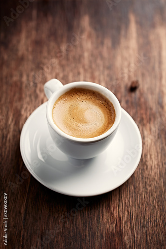 Cup of coffee on brown wooden background. 