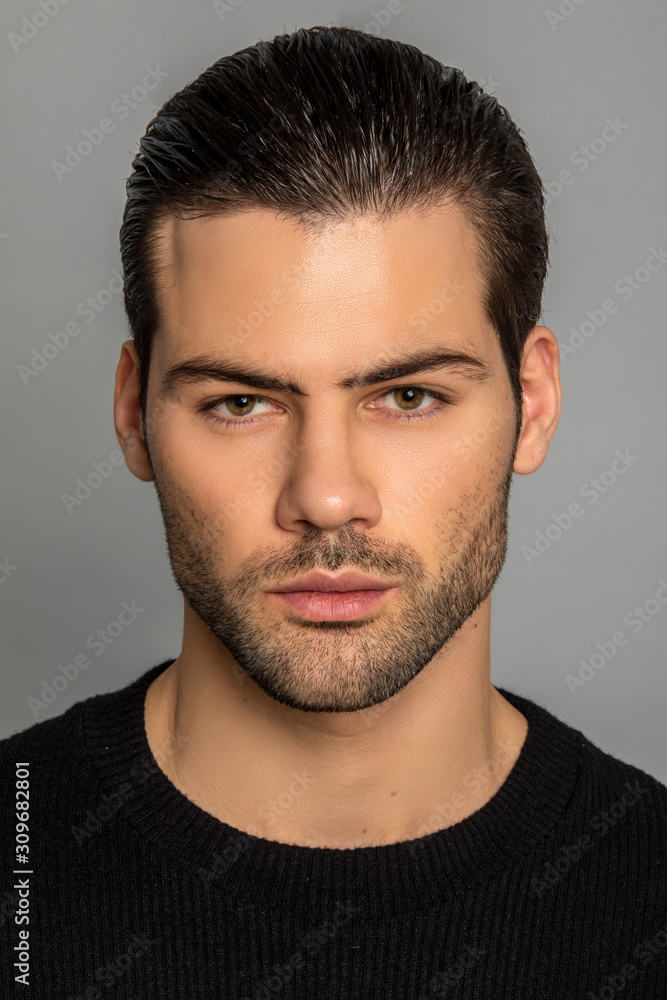 Fototapeta premium Muscle strong beautiful stripped male model in black jamper and black trousers on grey isolated font background