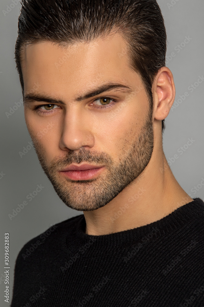 Muscle strong beautiful stripped male model in black jamper and black trousers on grey isolated font background Muscle strong beautiful stripped male model in black jamper and black trousers on grey isolated font background