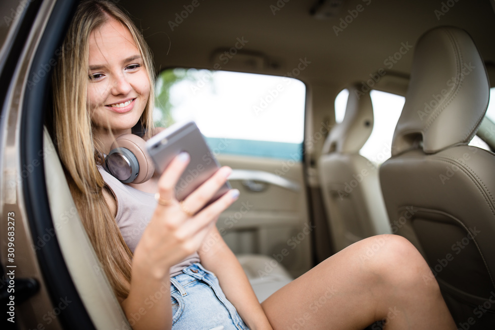 Cute teenage girl listening to her favorite music/audiobook on hig-end headphones during a roadtrip