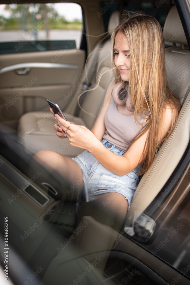 Cute teenage girl listening to her favorite music/audiobook on hig-end headphones during a roadtrip