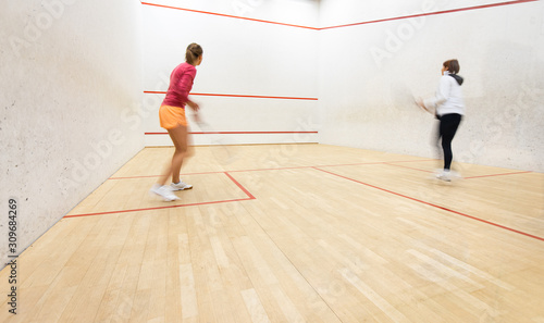 Two female squash players in action on a squash court (motion blurred image  color toned image) © lightpoet