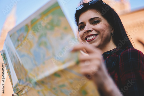 Fotografie Happy smiling female tourist searching way along street with destination map and