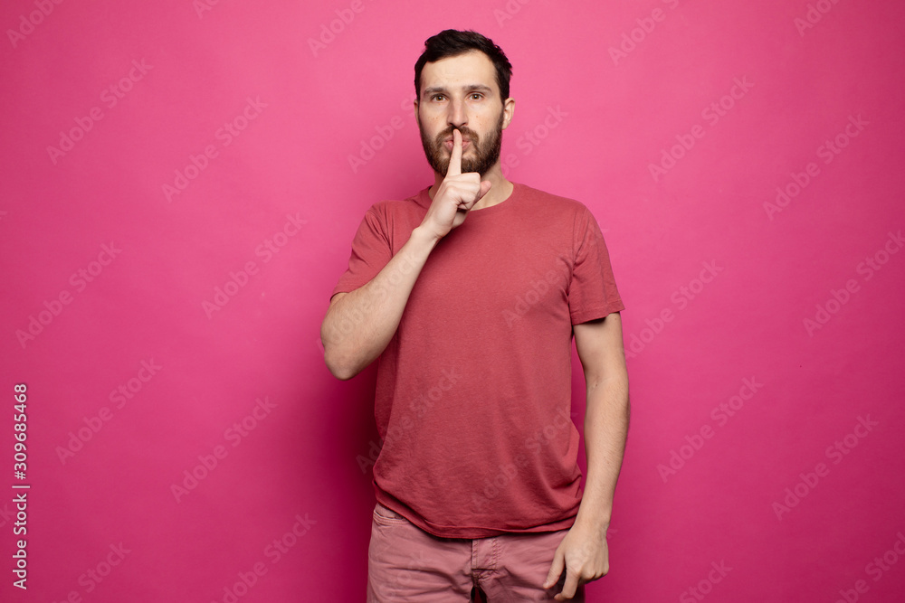 Fototapeta premium Bearded man placing finger on lips as if to say, shhhhh, be quiet, silence.