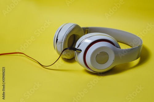 White cordless audio headphones on a yellow background.
