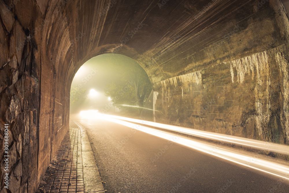 The Tunnel. Way out with spooky mist and fog at night with loght trails from car.