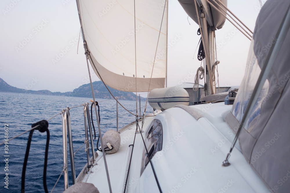 Fototapeta premium Boat trip on a yacht under sail, a fragment of the deck and the mountains on the horizon, the view from the deck.