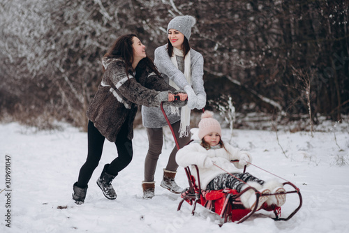 Happy family of three sledding on a winter walk near the forest