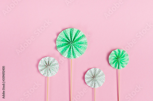 Round cake toppers on wooden sticks on pink background