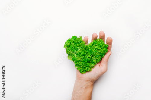 Heart shape stabilized moss in a hand on white background