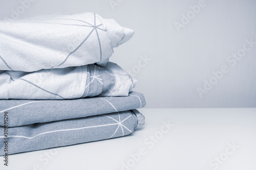 A stack of cozy home textile in shades of gray bed linen, bedding with copy space
