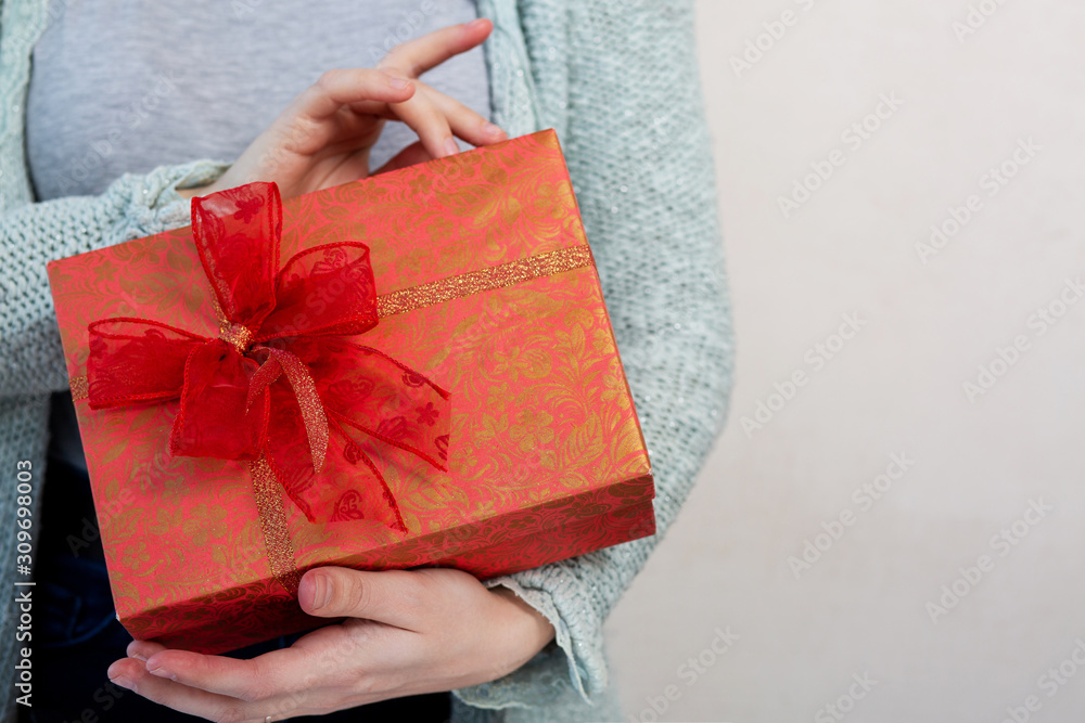 Woman's hands holding gift box over a grey background Woman's hands holding gift box over a grey background