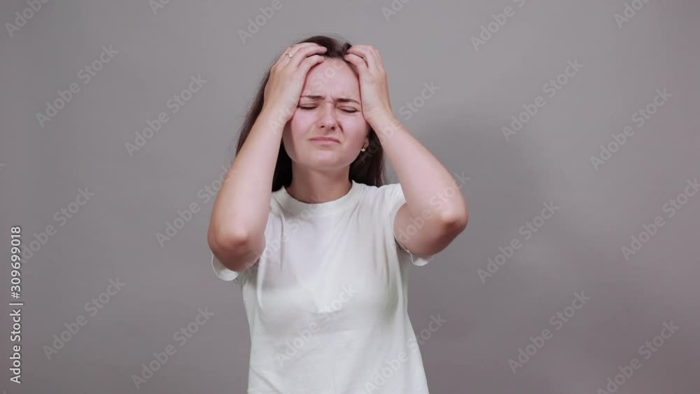 Attractive sickness caucasian young woman in fashion white shirt keeping hands on head, having headache isolated on gray background in studio. People sincere emotions, lifestyle concept. Attractive sickness caucasian young woman in fashion white shirt keeping hands on head, having headache isolated on gray background in studio. People sincere emotions, lifestyle concept.