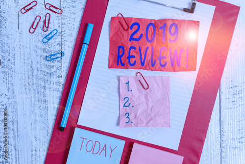 Text sign showing 2019 Review. Business photo text remembering past year events main actions or good shows Clipboard sheet crushed sticky note clip notepads marker wooden background photo