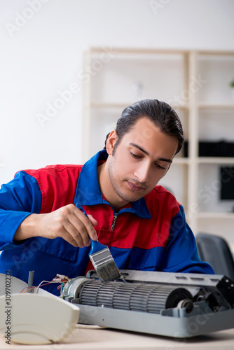 Young repairman repairing air-conditioner at warranty center