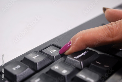 Hands are pressing black keyboard buttons,F12 button on the keyboard.