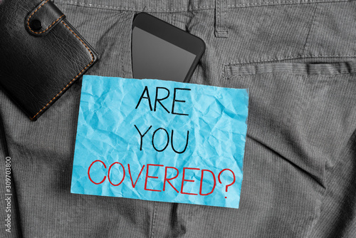 Text sign showing Are You Covered Question. Business photo text asking showing if they had insurance in work or life Smartphone device inside trousers front pocket with wallet and note paper