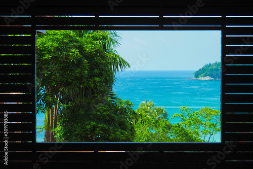 View of green trees and the blue sea through a wooden frame.     © Popel