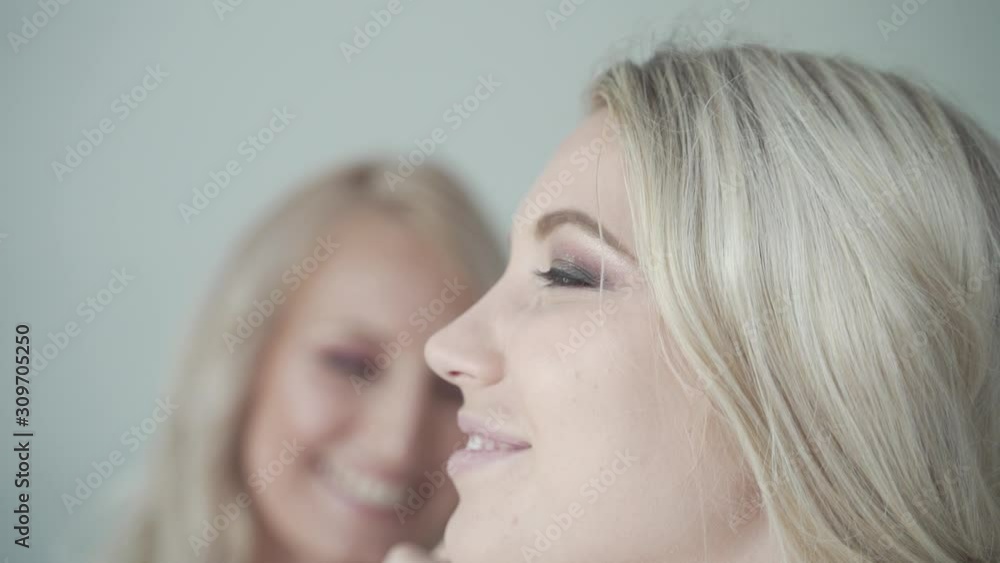 Make up artist at work apply powder to blond womens face both laughing and smiling - close medium shot Make up artist at work apply powder to blond womens face both laughing and smiling - close medium shot