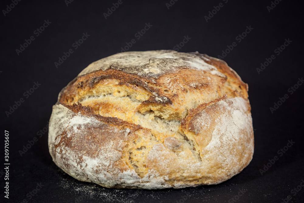 Loaf (or miche) of French sourdough, called as well as Pain de campagne, on display isolated on a black background. Pain de Campagne is a typical French huge loaf of bread abiding by traditional codes