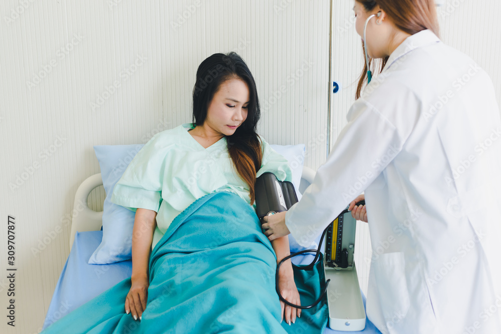 Obraz premium Asian women doctors come to measure the patient's pressure. Lying in the patient's bed