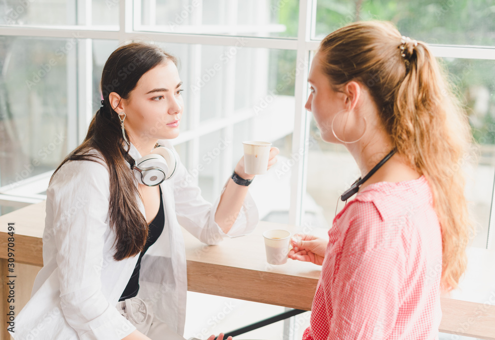 Two beautiful young women drinking coffee and talking together. concept of relaxation. Two beautiful young women drinking coffee and talking together. concept of relaxation.