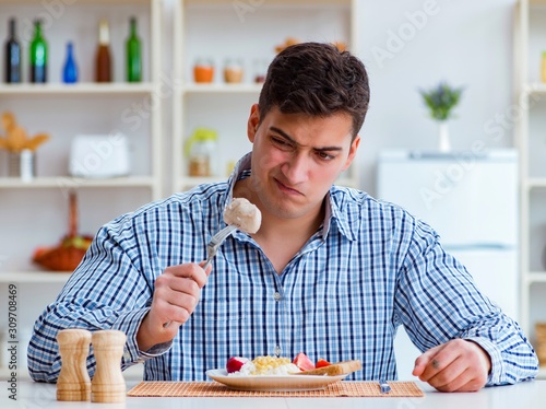 Man eating tasteless food at home for lunch photo