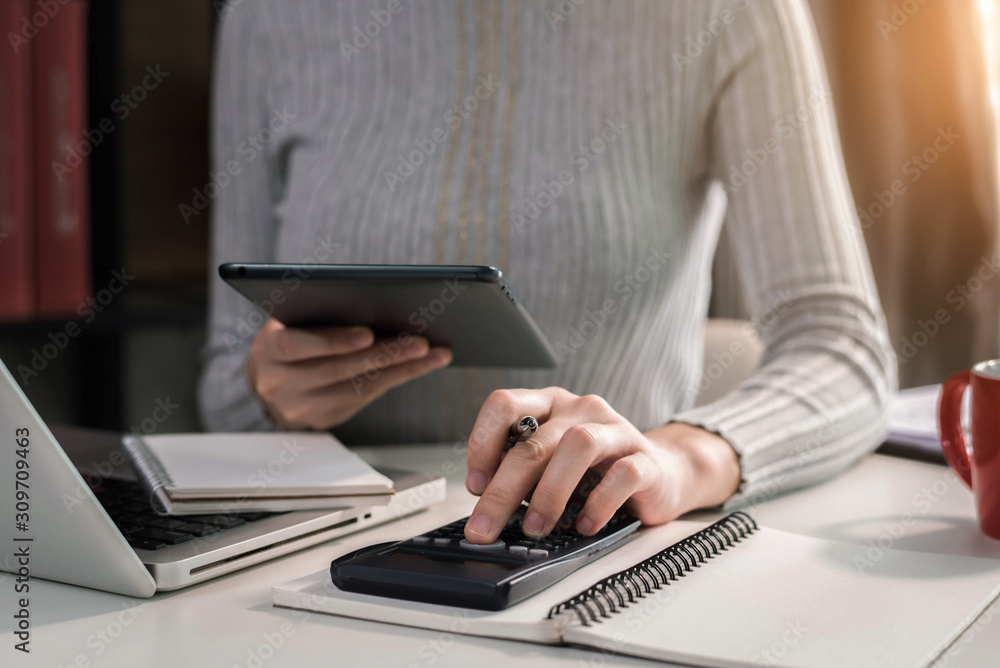 Female businessman hand using calculator and writing make note with calculate about cost at home office. Female businessman hand using calculator and writing make note with calculate about cost at home office.