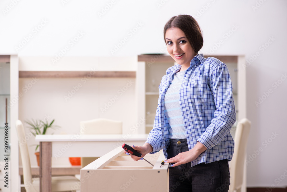 Young beautiful woman assembling furniture at home Young beautiful woman assembling furniture at home