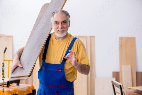 Old male carpenter working in workshop