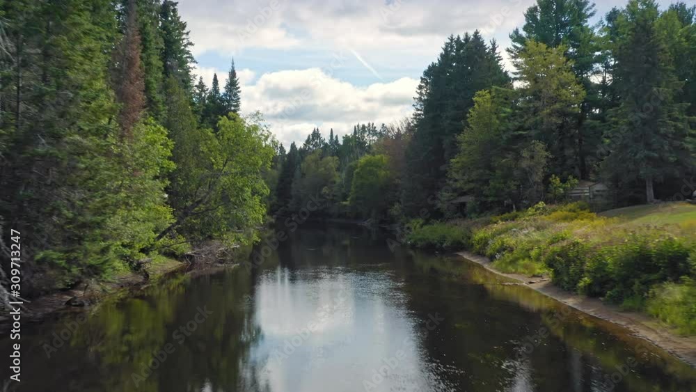 Aerial: Flying down a calm mirror river with forest. Val David, Quebec, Canada Aerial: Flying down a calm mirror river with forest. Val David, Quebec, Canada