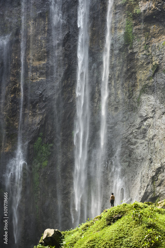 Stunning view of a tourist enjoying the view of the Tumpak Sewu Waterfalls. Tumpak Sewu Waterfalls also known as Coban Sewu are a tourist attraction in East Java  Indonesia.