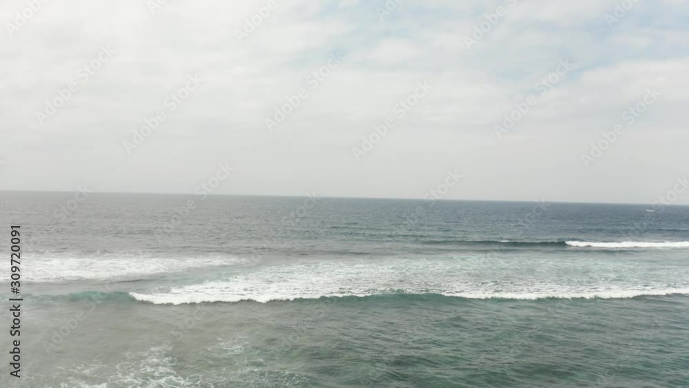 Close flyover Nusa Dua cliff with a drone in 4k. Amazing tropical palm and blue ocean with ocean horizon in background cloudy summer day in Bali Indonesia. Close flyover Nusa Dua cliff with a drone in 4k. Amazing tropical palm and blue ocean with ocean horizon in background cloudy summer day in Bali Indonesia.