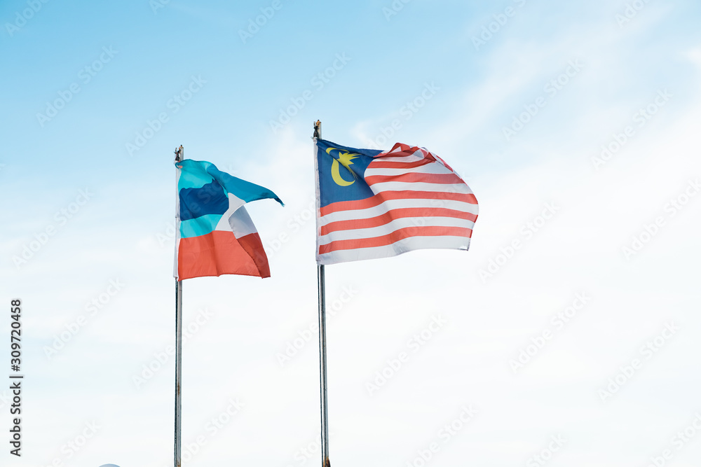 Malaysia and Sabah flags waving with blue sky in the background.