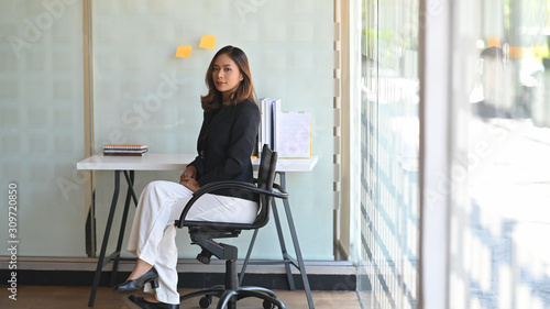 Beautiful asian businesswoman confidently smiling and sitting on modern office.