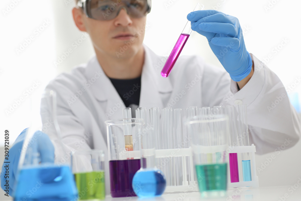 A male chemist holds test tube of glass A male chemist holds test tube of glass