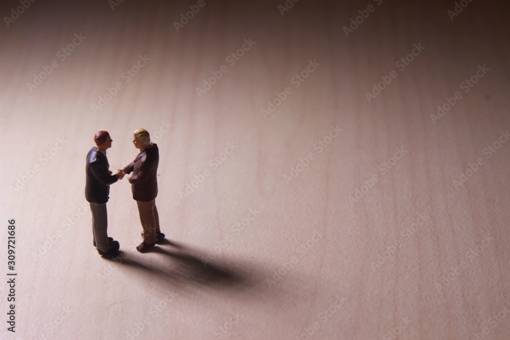 Dramatic Lighting, Simple Illustration Photo for Two Mini Figure Businesman Toy Handshaking for Business Agreement 