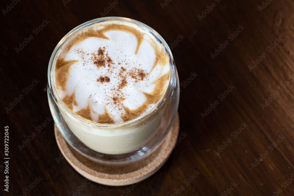 Close up white coffee cup with shape latte art foam on Brown wood table with light shade on tabletop at cafe. Close up white coffee cup with shape latte art foam on Brown wood table with light shade on tabletop at cafe.