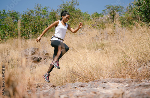 African american woman athlete runner exercise training and jumping outdoors in beautiful mountain nature landscape. Active health and motivation lifestyle and Adventure Concept. Fitness workout.