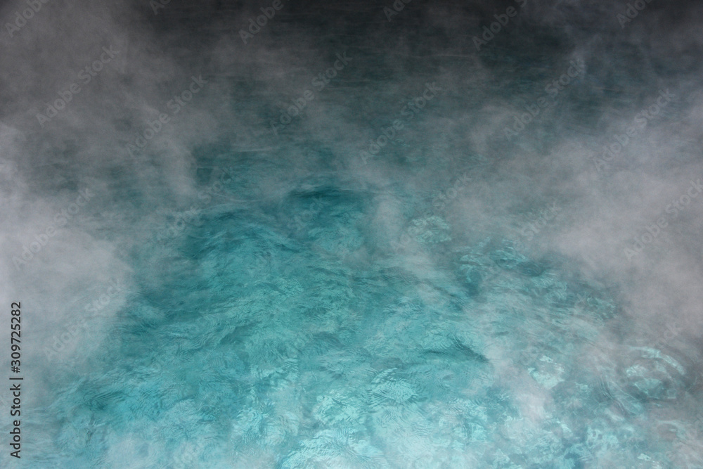 Pure clear water in the thermal pool. Hot water flows and fog rises above the pool, steam. Blue water, beautiful background.