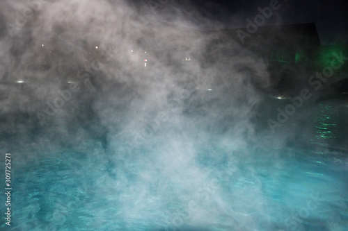 Pure clear water in the thermal pool. Hot water flows and fog rises above the pool, steam. Blue water, beautiful background.