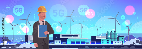 male engineer controlling wind turbine solar panel alternative energy source 5G online wireless system connection factory building industrial plant power station concept flat horizontal portrait