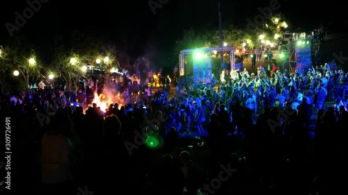 Celebration holiday feast. Night Beach Disco concert with colorful illumination and bonfire. Dancing people with fun gladness on the discotheque entertainment. Gaiety merriment of youth 